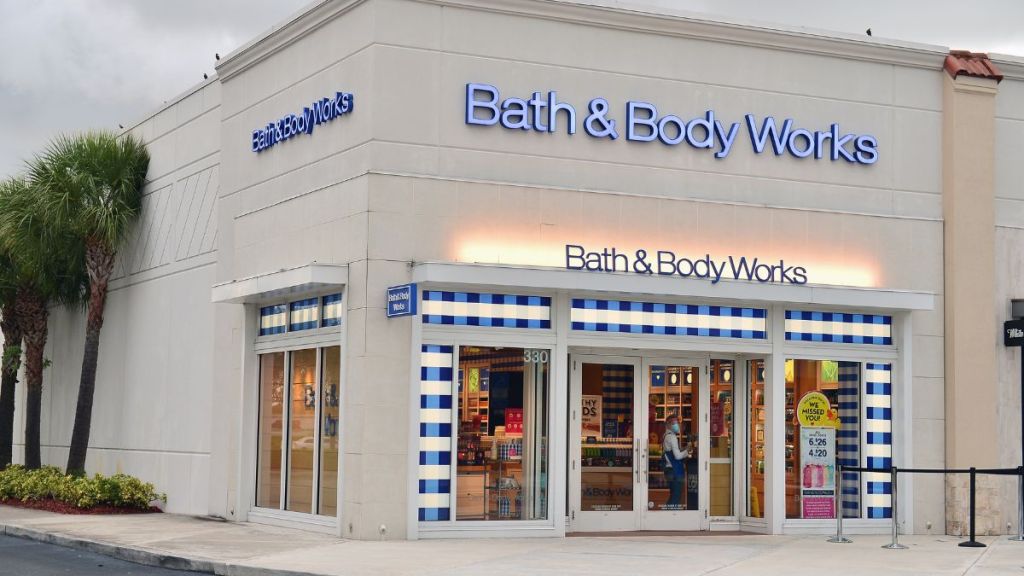 An employee with a face mask and shield cleans the door of Bath & Body Works store on July 21, 2020 in Pembroke Pines, Florida.
